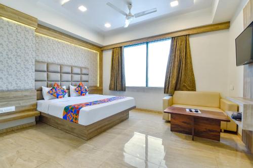 a bedroom with a bed and a tv and a couch at FabHotel Hill Park in Ahmedabad