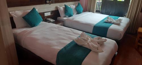 two beds in a room with blue and white at The Red House Bandipur in Bandipur