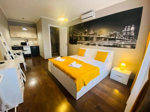 a bedroom with a bed with yellow sheets and a kitchen at 9 Borbalo Street Apartment with terrace in Tbilisi City