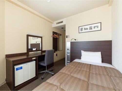 ein Hotelzimmer mit einem Bett, einem Schreibtisch und einem Spiegel in der Unterkunft The OneFive Okayama - Vacation STAY 41839v in Okayama