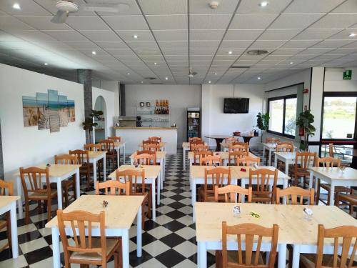 un ristorante con tavoli e sedie in legno e pavimento a scacchi di Hotel Baia del Cigno a Torre San Giovanni Ugento