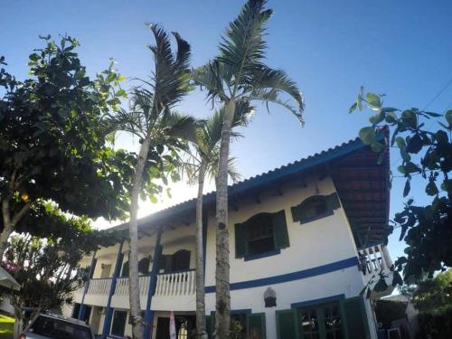 a house with palm trees in front of it at condominio colonial pousada mariscal in Canto Grande