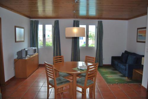 a living room with a table and chairs and a couch at Apartamentos Turisticos Nossa Senhora Da Estrela in Lagoa