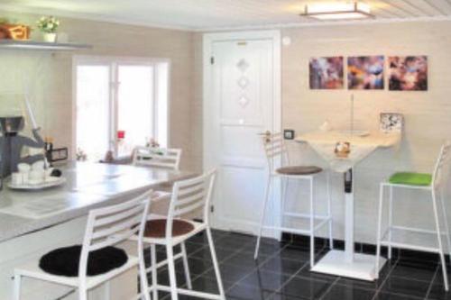 a kitchen with white chairs and a counter and a table at Modern stuga med sjöutsikt in Hammarby