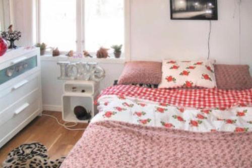Schlafzimmer mit einem Bett mit einer roten und weißen Decke in der Unterkunft Modern stuga med sjöutsikt in Hammarby