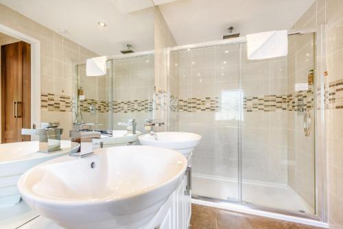- Baño blanco con 2 lavabos y ducha en Bay Tree Lodge 02, en Narberth