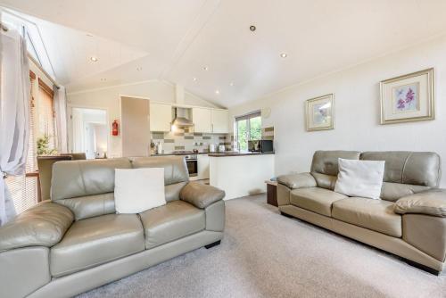a living room with two leather couches and a kitchen at Bay Tree Lodge 02 in Narberth