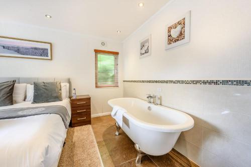 a white bathroom with a bed and a bath tub at Bay Tree Lodge 02 in Narberth