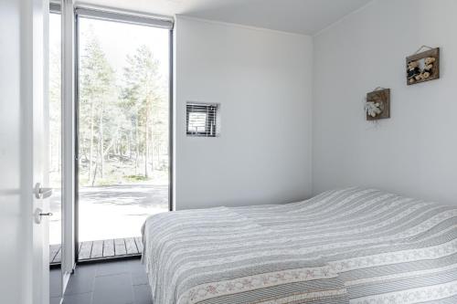 een witte slaapkamer met een bed en een raam bij Seaview villa with jacuzzi in Töfsala