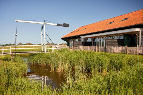 a barn with a wind turbine next to a pond at Dutchen Erfgoedpark De Hoop Vakantiewoningen in Uitgeest