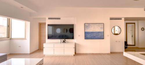 uma sala de estar com televisão e uma cómoda branca em BnBIsrael apartments - Dizengoff Anemone em Tel Aviv