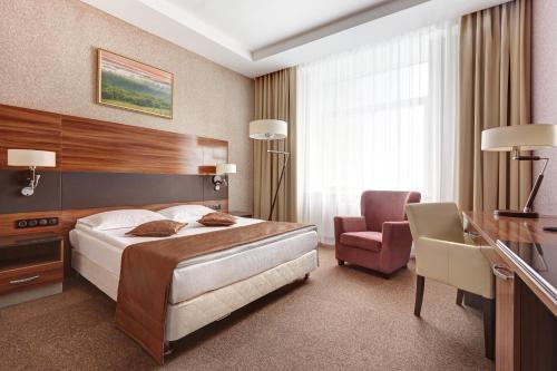 una camera con letto, scrivania e sedia di Victoria Olimp Hotel & Business centre Minsk a Minsk