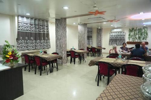 ein Restaurant mit Tischen und Stühlen und Menschen, die darauf sitzen in der Unterkunft Hotel Avon International in Aurangabad