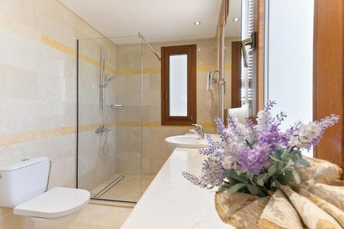 a bathroom with a toilet and a shower and a vase of flowers at 4 bedroom Villa Galinios with large private pool, Aphrodite Hills Resort in Kouklia