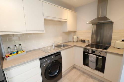 uma cozinha com armários brancos e uma máquina de lavar louça em The Hive - IH21ALL - APT 2 em Thornaby on Tees