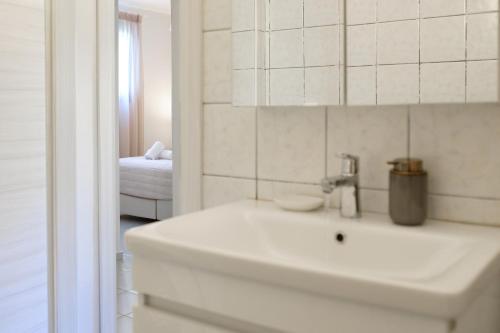 a white bathroom with a sink and a bedroom at Golden Aura in Danilia