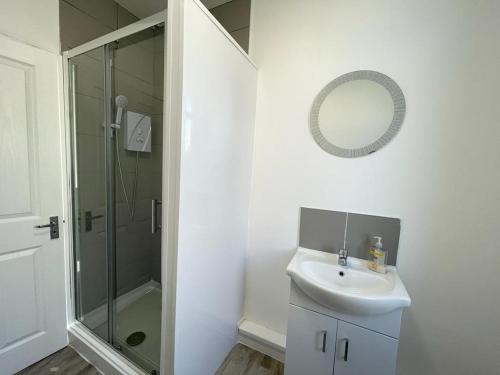 uma casa de banho branca com um lavatório e um chuveiro em The Central Suite Sasco Apartments em Blackpool