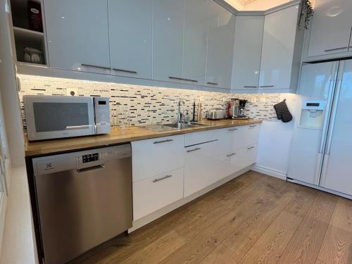 a kitchen with white cabinets and a sink and a microwave at Stunning 5BR 16 Bed Home with Finnish Sauna & Jacuzzi 340 m2 in Tampere