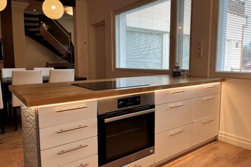 a kitchen with white cabinets and a stove top oven at Stunning 5BR 16 Bed Home with Finnish Sauna & Jacuzzi 340 m2 in Tampere