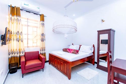 a bedroom with a bed and a chair and a window at Dodoma Shine Lodge in Dodoma