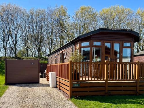 a large wooden cabin with a deck and a gate at Stags Head Lodge in Felton