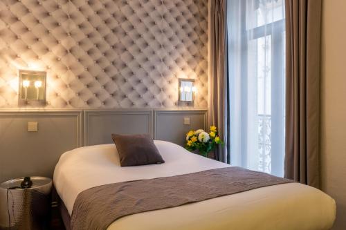 a bedroom with a bed and a window at Hôtel de France in Toulouse