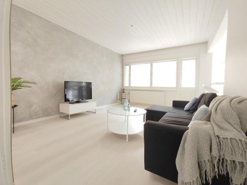 sala de estar con sofá negro y TV en City Style en Jyväskylä