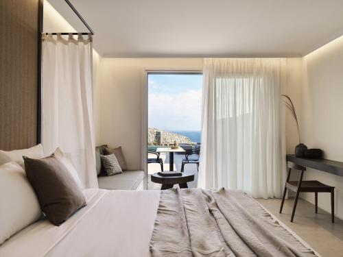 a bedroom with a bed and a balcony with a table at Ezio Bo Luxury Living in Mýkonos City