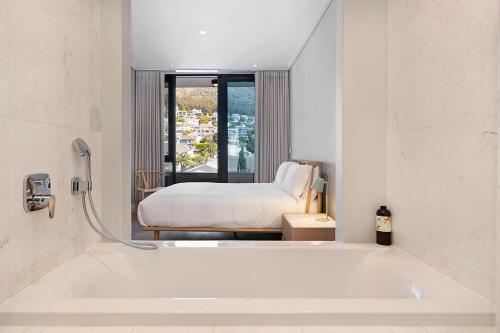 une baignoire blanche dans une chambre avec un lit dans l'établissement 35 On Main by Stay In Luxury, au Cap