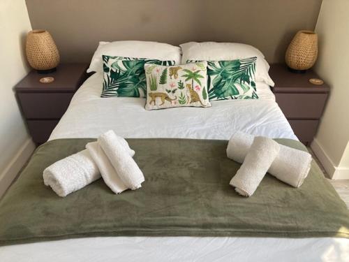 a bed with three pillows and a green blanket at The Salt Box- Lovely refurbished annexe, free parking, walk to Porth beach. in Saint Columb Minor