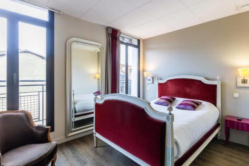 una camera con letto rosso e specchio di Hôtel de France a Tolosa