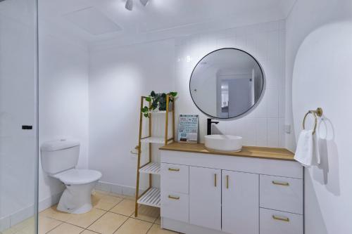 uma casa de banho branca com um WC e um espelho. em Zion Escapes Cairns City Waters Edge Family Apartment em Cairns