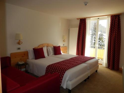 a hotel room with a bed and a red couch at Hotel Schweizerhof Pontresina in Pontresina