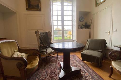 d'un salon avec une table, des chaises et une fenêtre. dans l'établissement Large castle with garden near Caen, 