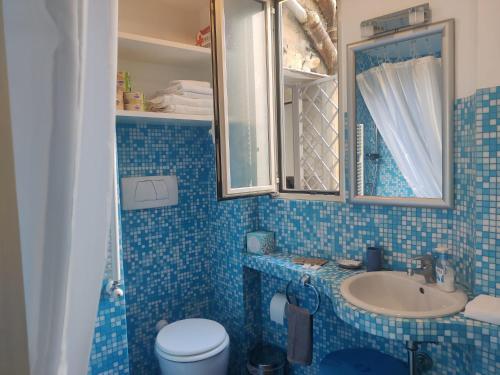 Un baño con azulejos azules, lavabo e inodoro. en Warm Charming Apartment in Campo de Fiori, en Roma