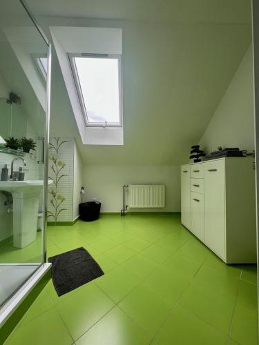 a bathroom with a green tile floor and a window at Ubytování Zátiší 2 Olomouc in Olomouc