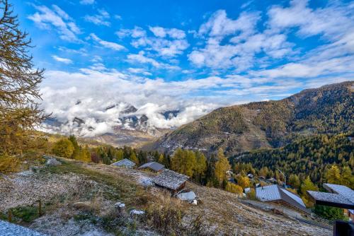 a small village on a hill with mountains in the background at Chalet Claire de Soleil in La Tzoumaz