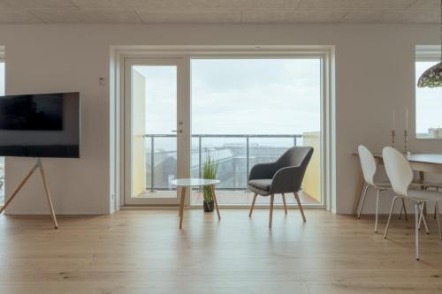 sala de estar con mesa, sillas y TV en New 2BR Apartment / Sea View, en Tórshavn