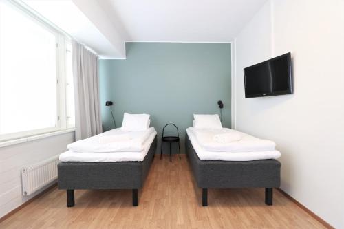 two beds in a room with a tv on a wall at Forenom Aparthotel Helsinki Herttoniemi in Helsinki