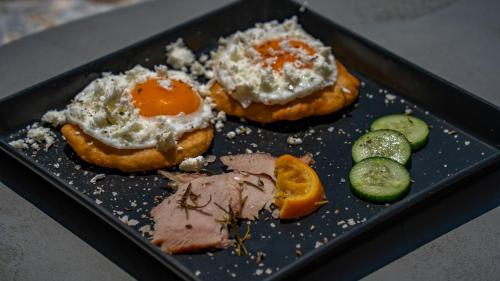 a plate of food with eggs and meat and cucumbers at Alika Resort in Álika