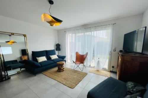 ein Wohnzimmer mit einem blauen Sofa und einem TV in der Unterkunft A charming house in Puilboreau in Puilboreau