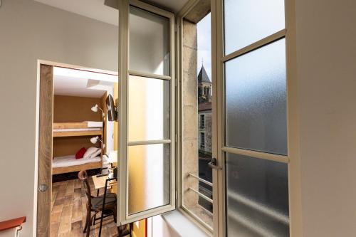 una habitación con una puerta corredera de cristal y un dormitorio en L'Auberge des Artistes, en Nieul-sur-lʼAutise