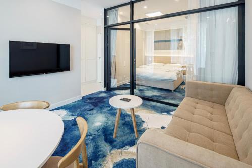 ein Wohnzimmer mit einem Sofa, einem TV und einem Bett in der Unterkunft VacationClub - Boulevard Residence Apartament 1 in Ustronie Morskie