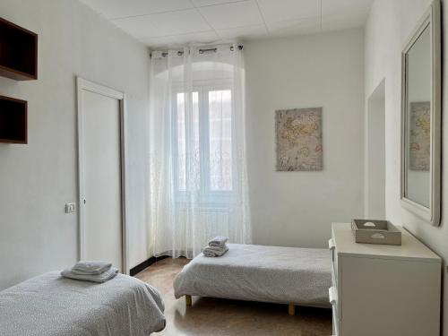 una stanza bianca con due letti e una finestra di Home Dolce Casa Apartment a La Spezia