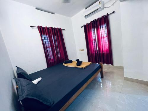 a bed in a room with red curtains at SAND BEACH HOUSE VARKALA in Varkala