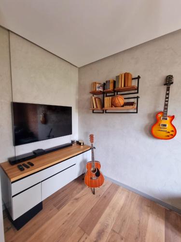 a living room with a flat screen tv and two guitars at Luksusowy Apartament Przy Sądzie Toruń in Toruń