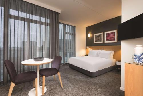 コペンハーゲンにあるアディナ アパートメント ホテル コペンハーゲンのベッド、テーブル、椅子が備わるホテルルームです。