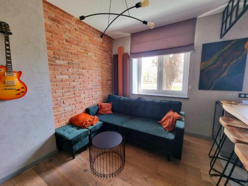 a living room with a blue couch and a brick wall at Luksusowy Apartament Przy Sądzie Toruń in Toruń
