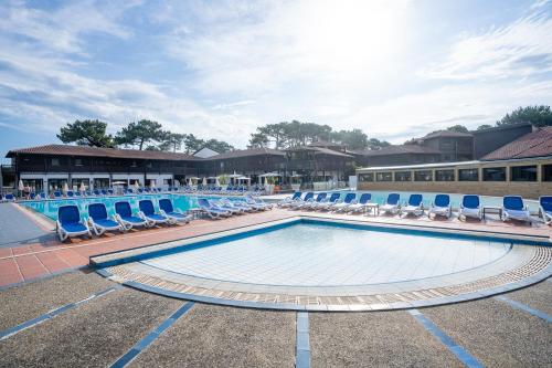 une grande piscine avec des chaises longues dans l'établissement Villages Clubs du Soleil - SOUSTONS - Locatif, à Soustons
