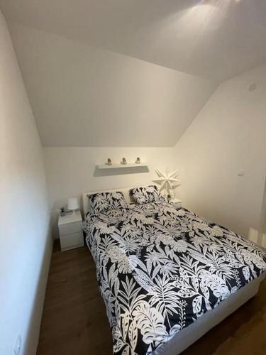 1 dormitorio con 1 cama con edredón blanco y negro en Kuća za odmor u prirodi NINA Jezero Orahovica, en Duzluk